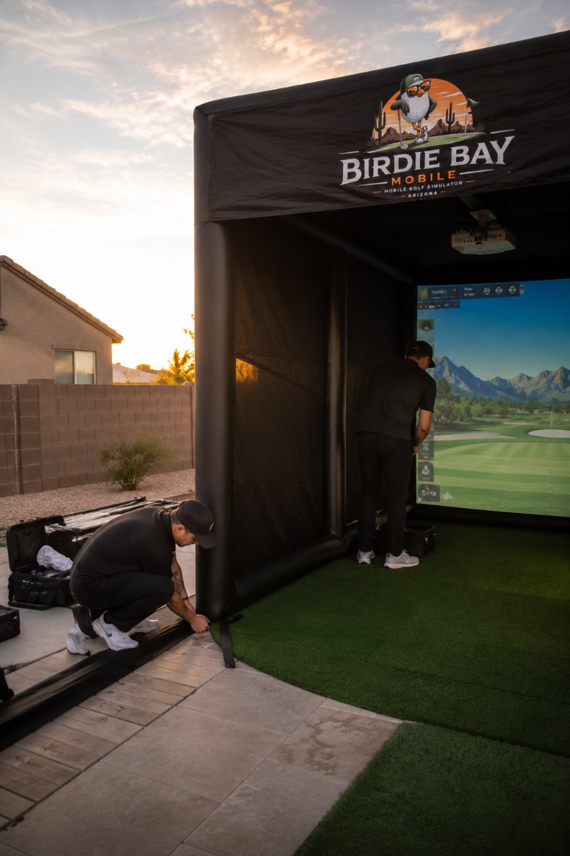 Justin and Andrew setting up the Birdie Bay Mobile inflatable golf simulator bay in a Gilbert, Arizona backyard at sunset